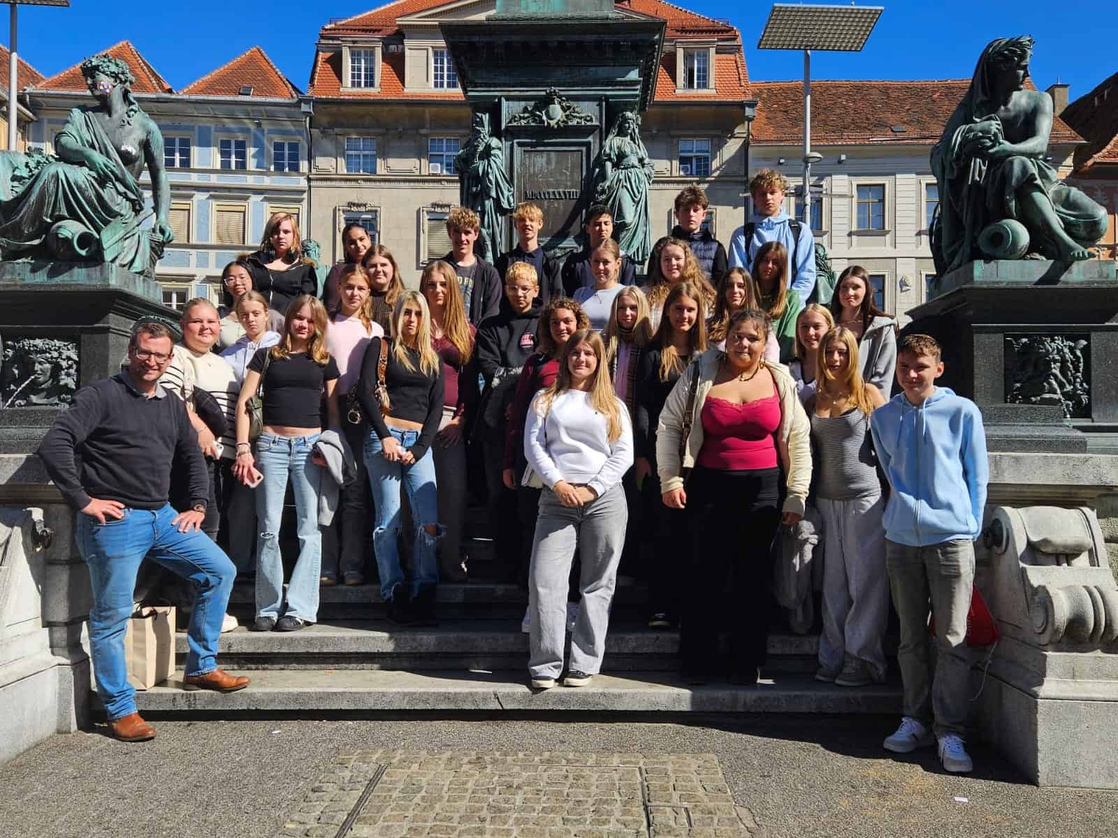 Schülergruppe mit Lehrer vor Denkmal am Grazer Hauptplatz
